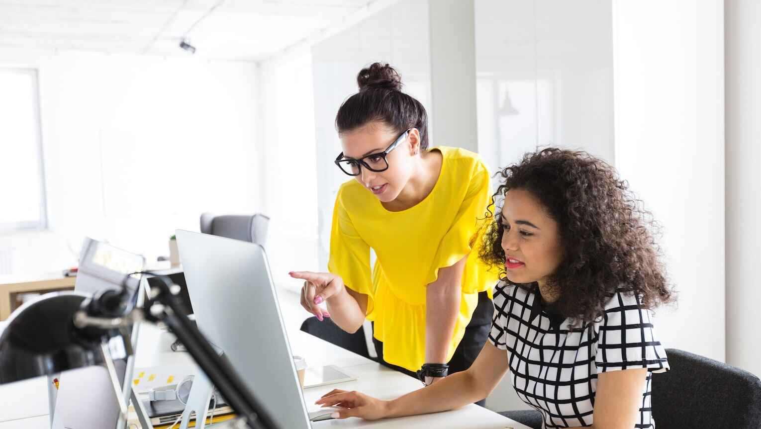 Two women looking at a computer monitor.